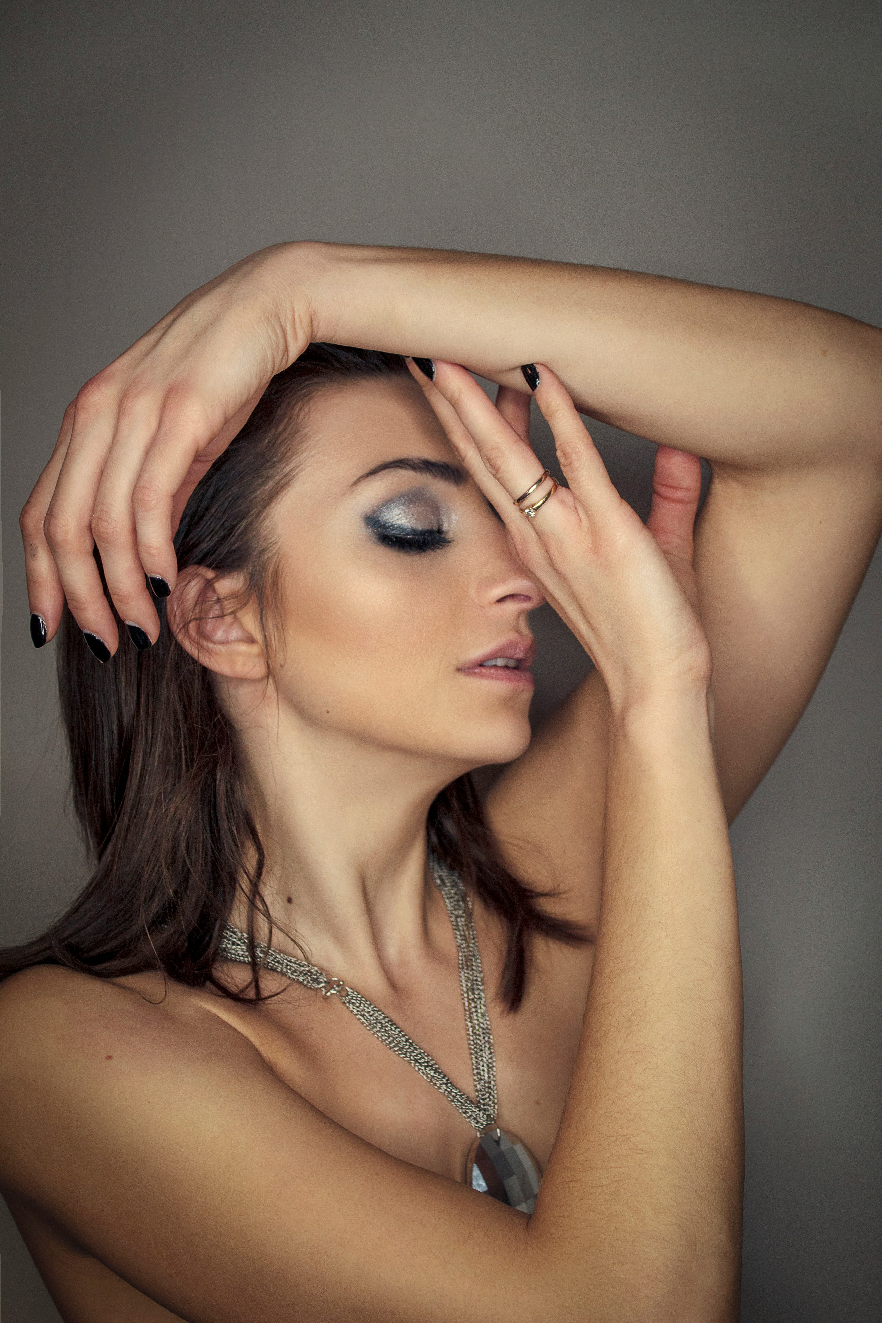 woman in silver necklace covering her face with her hand